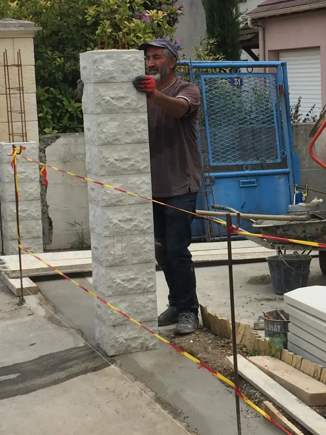 Efendi Yilmaz, artisan maçon, mettant en place un pilier en pierre reconstituée sur un chantier de clôture